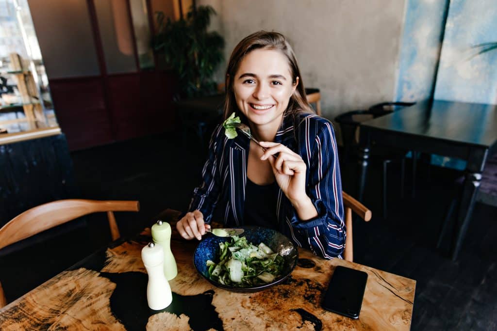 good humoured caucasian woman enjoying healthy food indoor shot of smiling girl eating salad